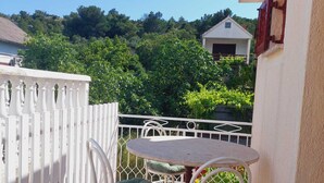 A balcony with a white fence, a round table, and two chairs with green cushions. - Apartments Tisno - one bedroom (left) (Tisno)