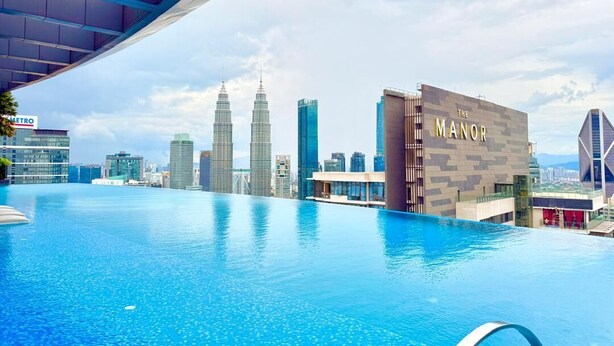 Una piscina infinita en la azotea, con el horizonte de la ciudad al fondo, incluyendo las Torres Petronas.