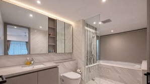 Un baño moderno con un espejo grande, inodoro, cabina de ducha y bañera.