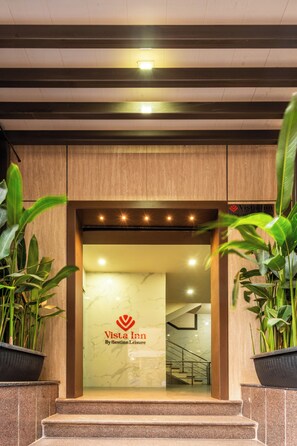 Entrada de un hotel con un cartel que dice 'Vista Inn By Bestinn Leisure', una pared de mármol y una escalera que conduce al interior.
