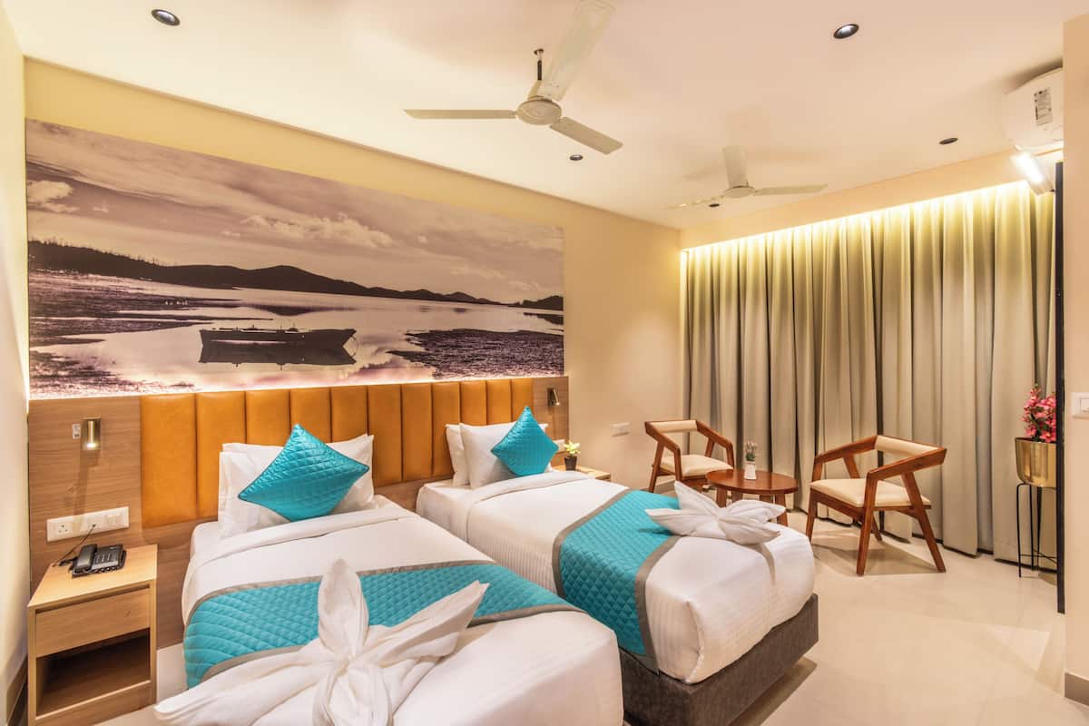 A hotel room with two beds, a large landscape painting, a ceiling fan, and a view of the outdoors.