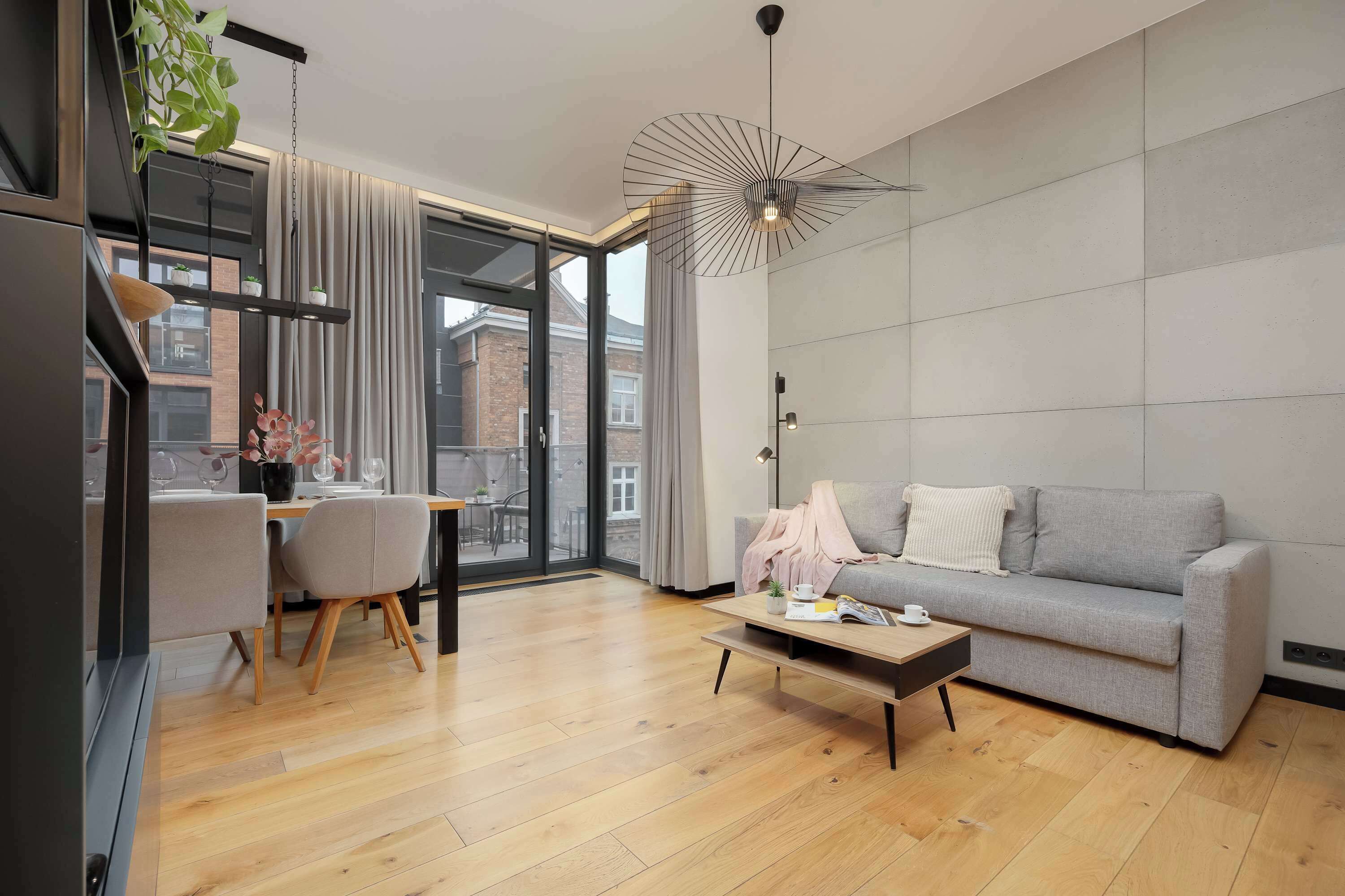 A modern living room with a grey sofa, wooden coffee table, and a dining area with a table and chairs.