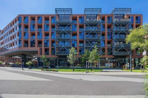 En moderne bygning med flere etager, store vinduer og et overdækket indgangsparti.