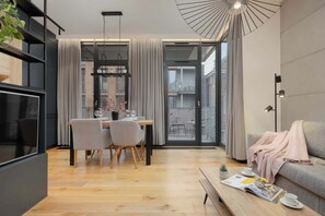 Ein modernes Wohnzimmer mit Essbereich, einer Couch, einem Couchtisch und Blick durch eine Glastür.