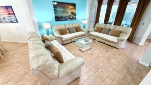 Ein Wohnzimmer mit einem Ecksofa, einem Couchtisch und einem Gemälde an der Wand.
