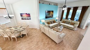 Ein Wohnzimmer mit einer Couch, einem Esstisch mit Stühlen und einem Deckenventilator.