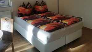 Un dormitorio con una cama, una mesita de noche, una lámpara y dos adornos en la pared.