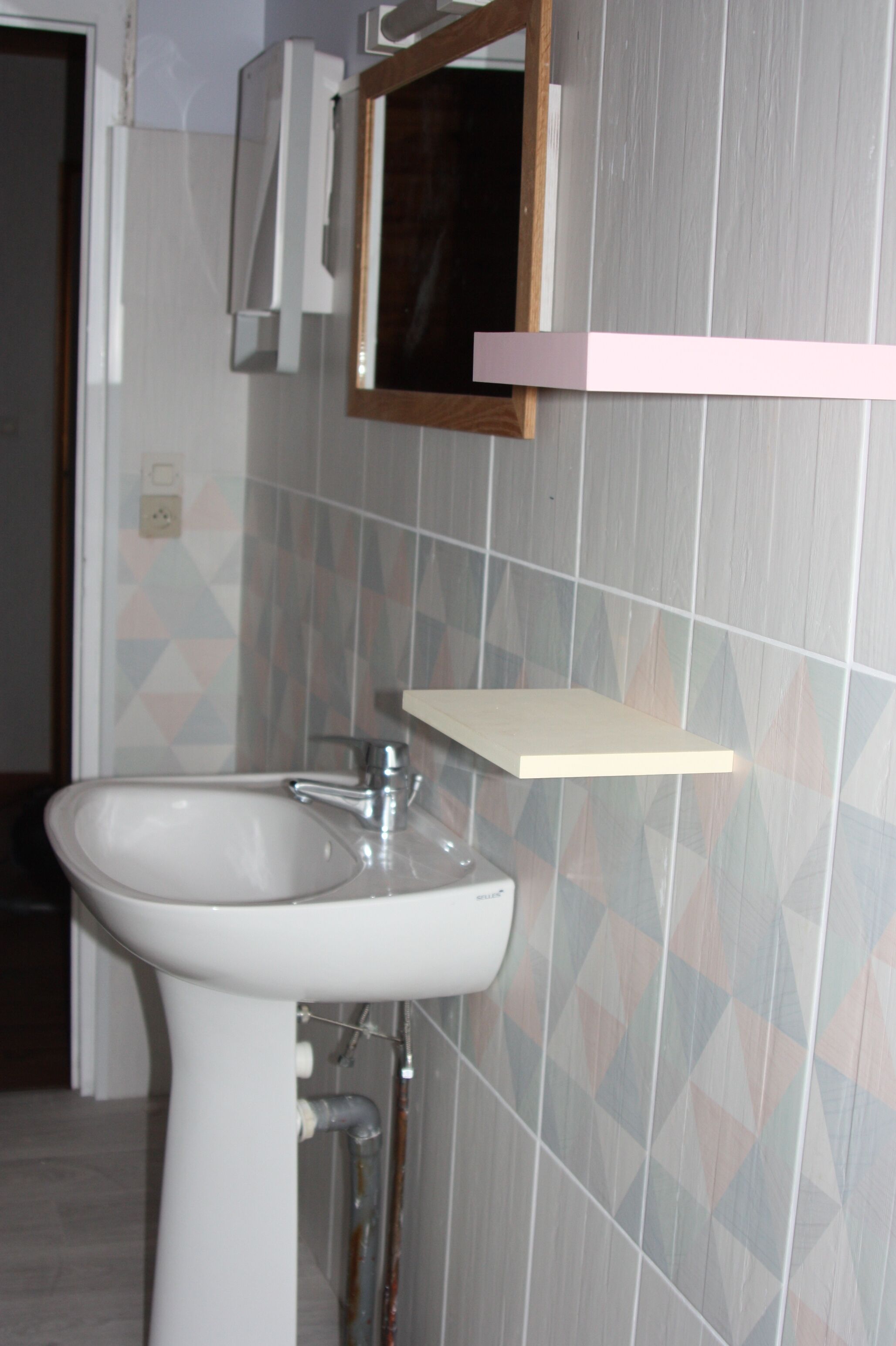 Une salle de bain avec un lavabo blanc, un miroir et un porte-serviettes.