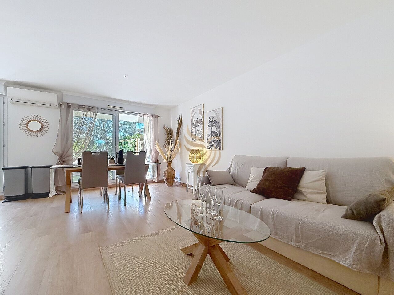 Una sala de estar moderna con una mesa de centro de vidrio, un sofá y una zona de comedor con sillas.