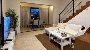 A modern living room with a white sofa, a coffee table, a TV, and a staircase. - Cozy studio at Portillo, Las Terrenas (Las Terrenas. El Portillo Residences.)