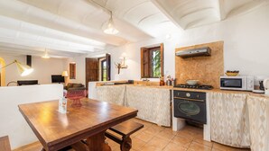 A kitchen with a wooden table, a stove, a microwave, and a sink. - Authentic Mallorcan House with Pool and Sea Views (Son Ferrandell)