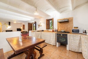 Una cocina con una mesa de madera, estufa, microondas y un lavamanos.