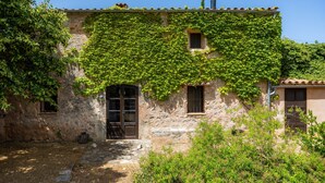 A rustic stone building with ivy-covered walls, a wooden door, and a small window. - Authentic Mallorcan House with Pool and Sea Views (Son Ferrandell)