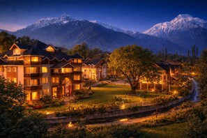 A multi-story hotel with a well-lit garden and a view of snow-capped mountains. - Faiz Resort Pahalgam (Pahalgam)