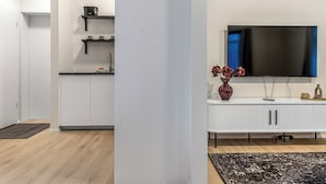 A modern kitchen with white cabinets, a black countertop, and a flat-screen TV mounted on a white cabinet. - Týsgata Apartments by Heimaleiga (Reykjavík)