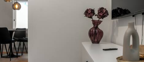 Een modern interieur met een witte console tafel, een vaas met bloemen en hanglampen.