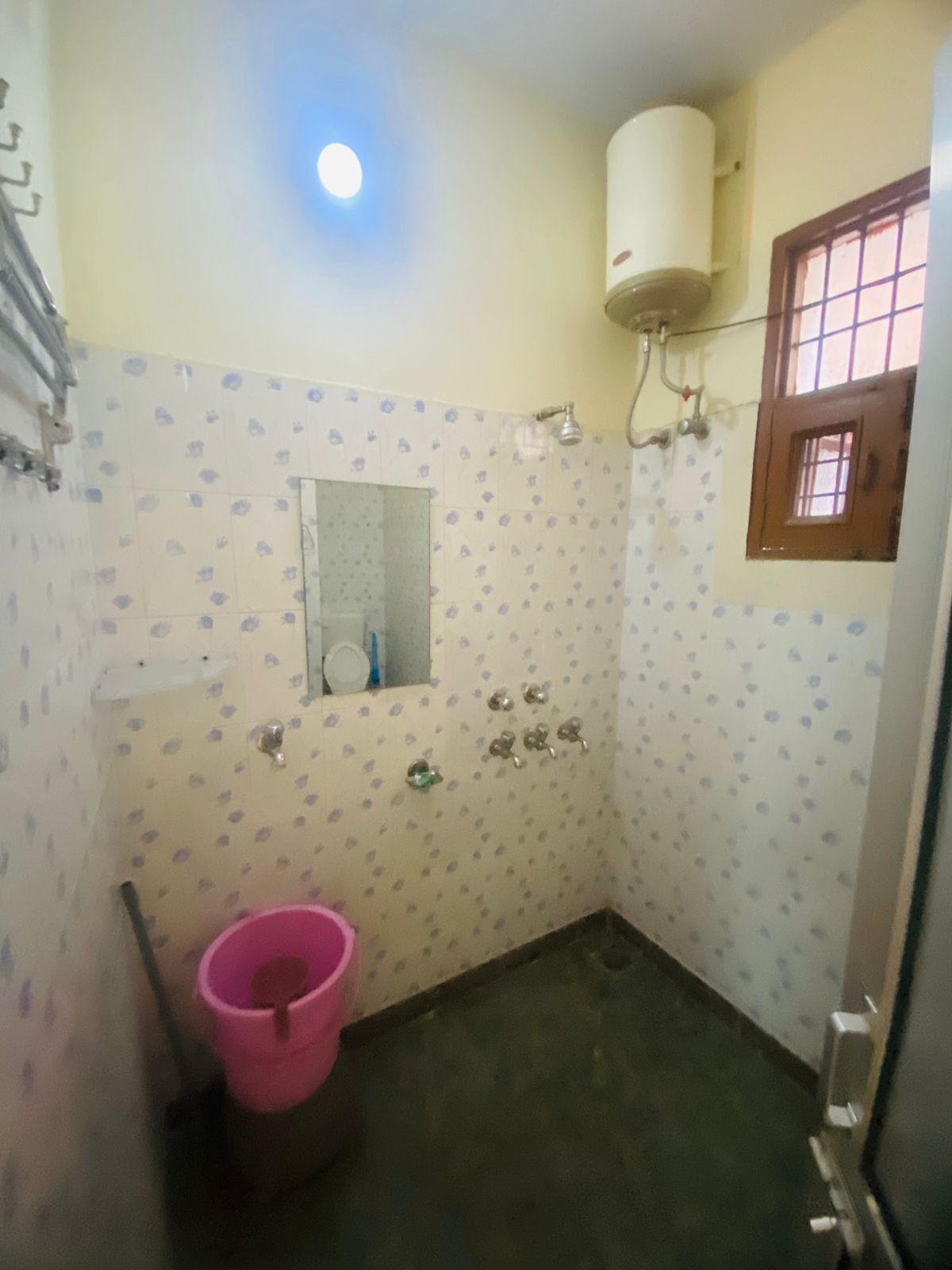 Een compacte badkamer met toilet, wastafel, spiegel, douche en boiler.