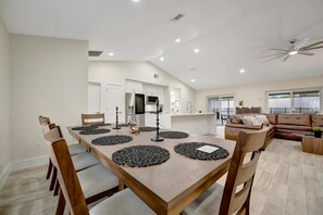 A spacious dining area with a long table, chairs, and a ceiling fan. - 5-Bed Disney Oasis w/ Pool & Arcade (Kissimmee)