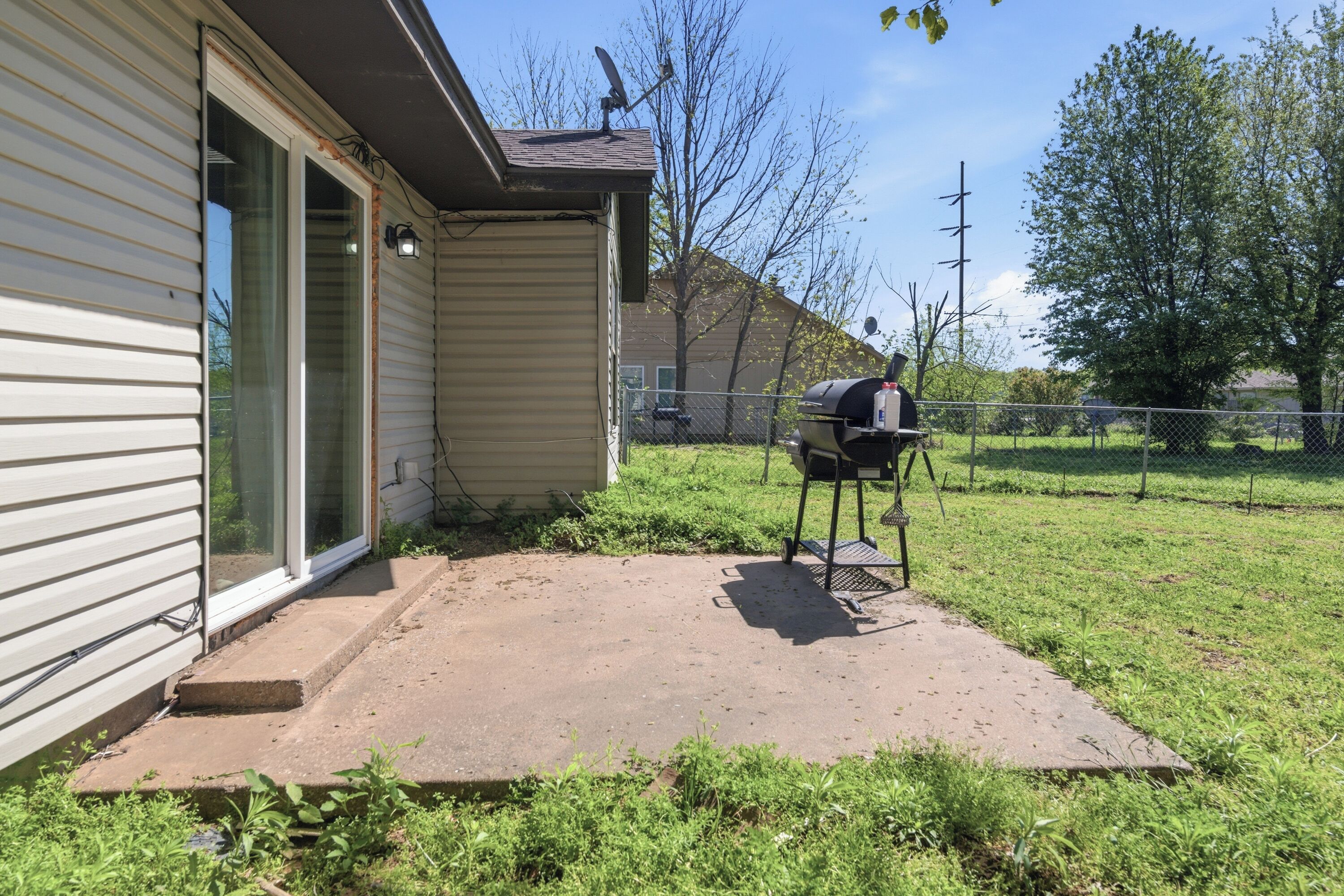 A house with a covered patio, a grill, and a satellite dish.
