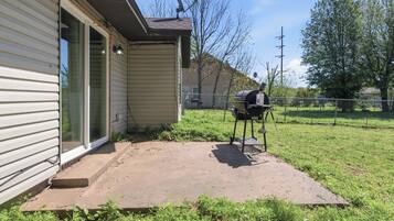 A house with a covered patio, a grill, and a satellite dish.