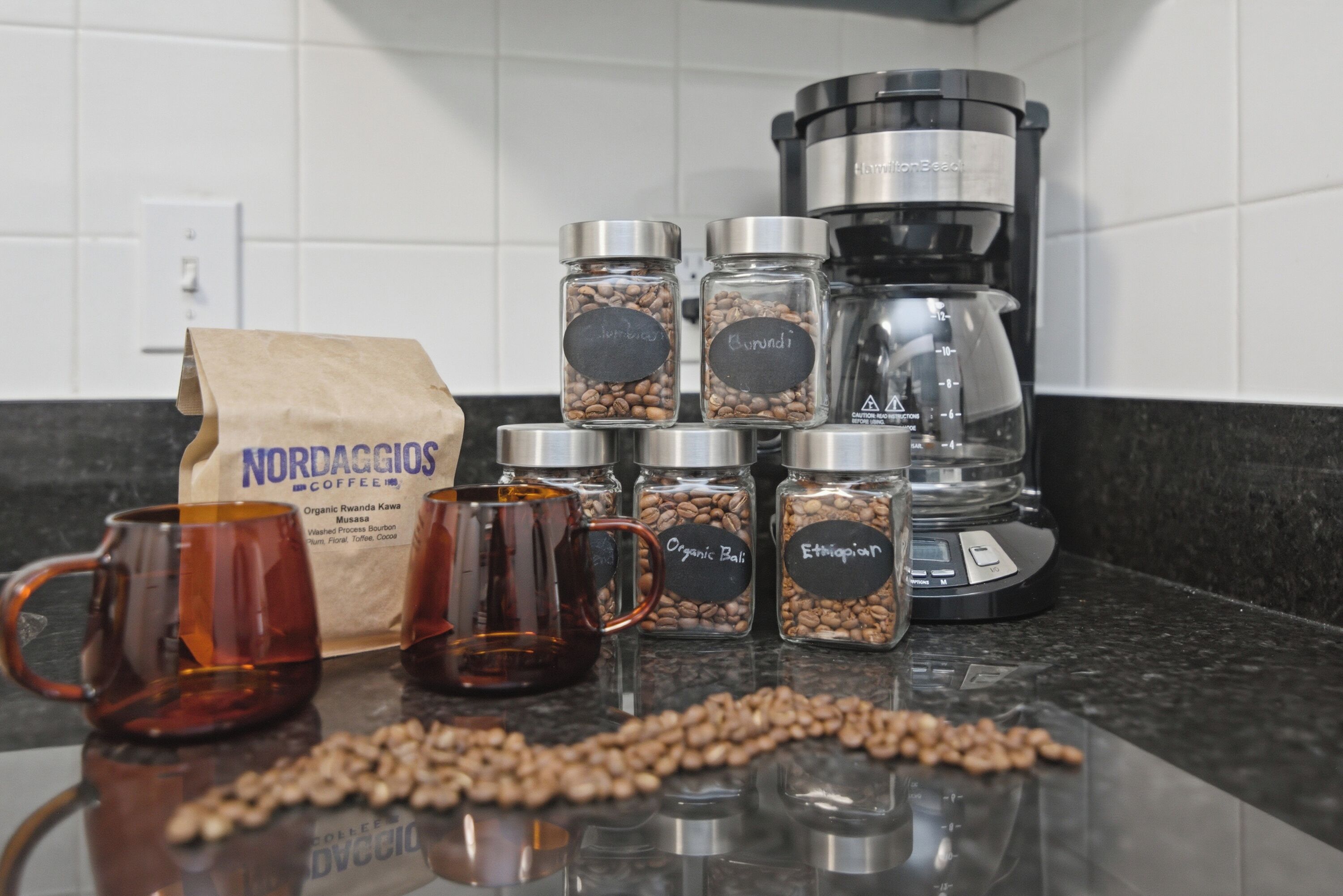 Un comptoir de cuisine avec des grains de café, une machine à café et deux tasses.