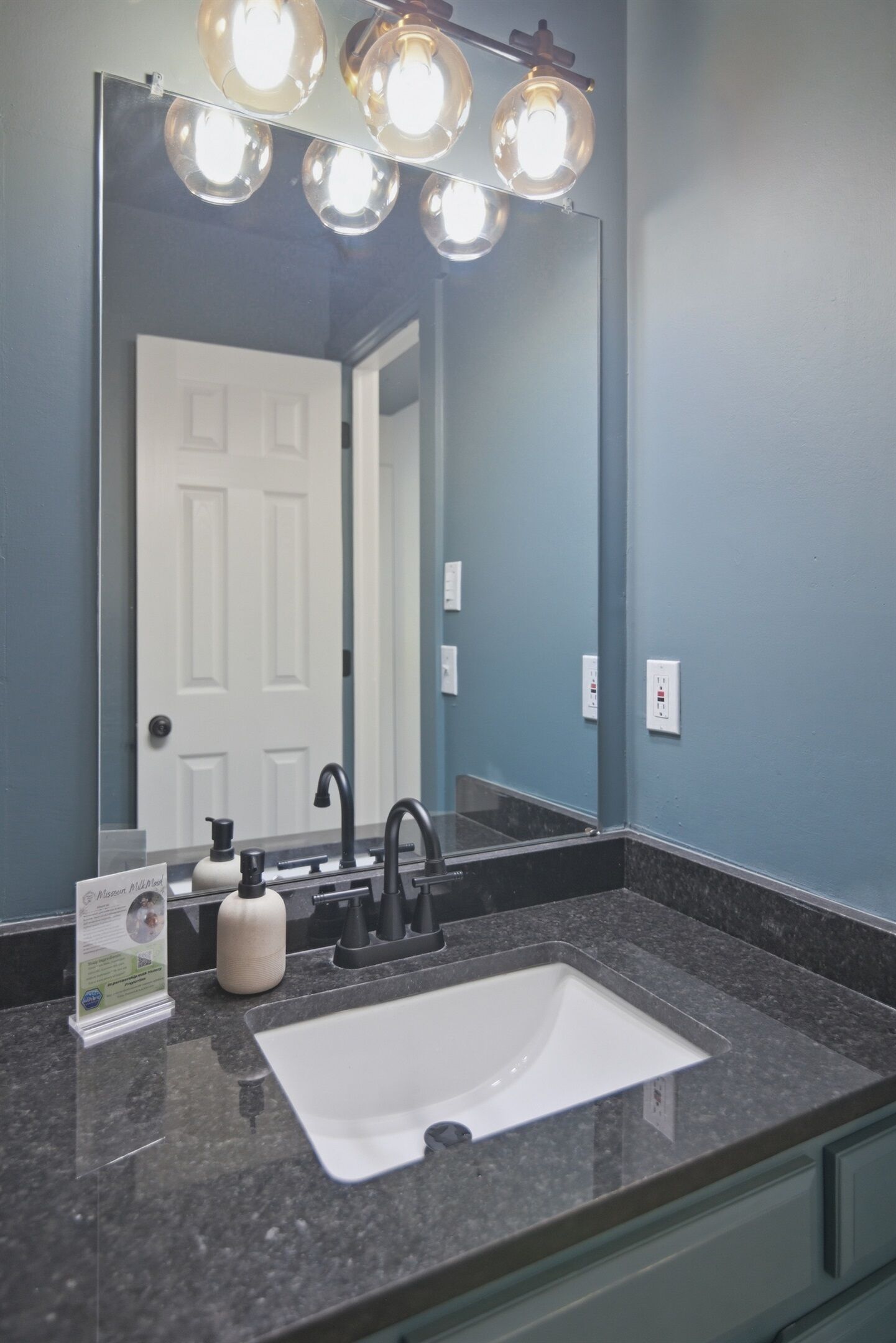 A bathroom with a large mirror, a sink, and a vanity.