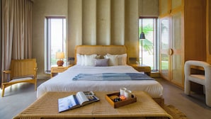 A hotel room with a large bed, a reading area with a magazine, a tray with candles, and a ceiling fan. - Elivaas Villa Fiorita Stuning 3BHK Villa (Jamwa Ramgarh)
