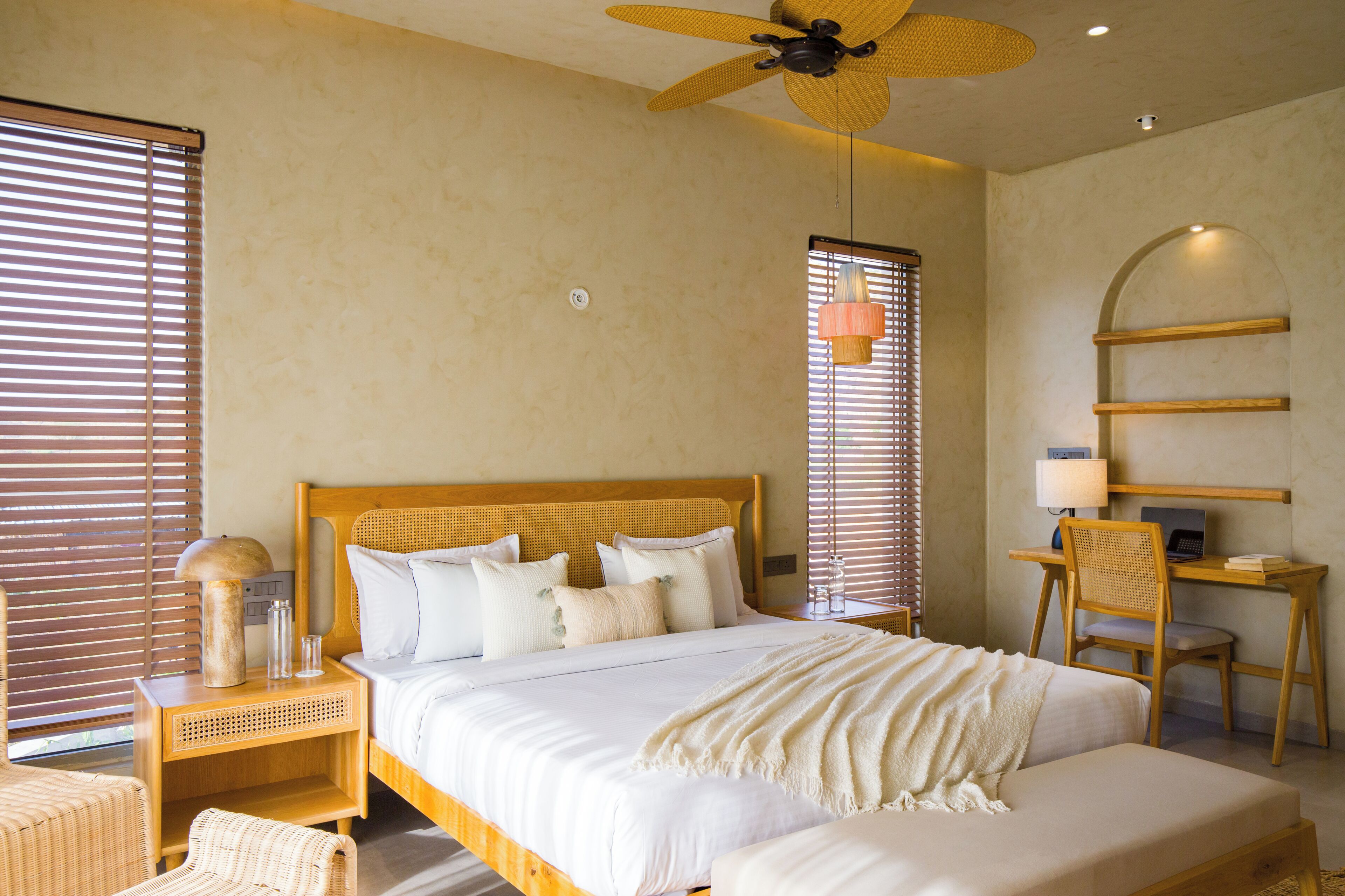 A bedroom with a bed, bedside tables, a desk, and a chair.