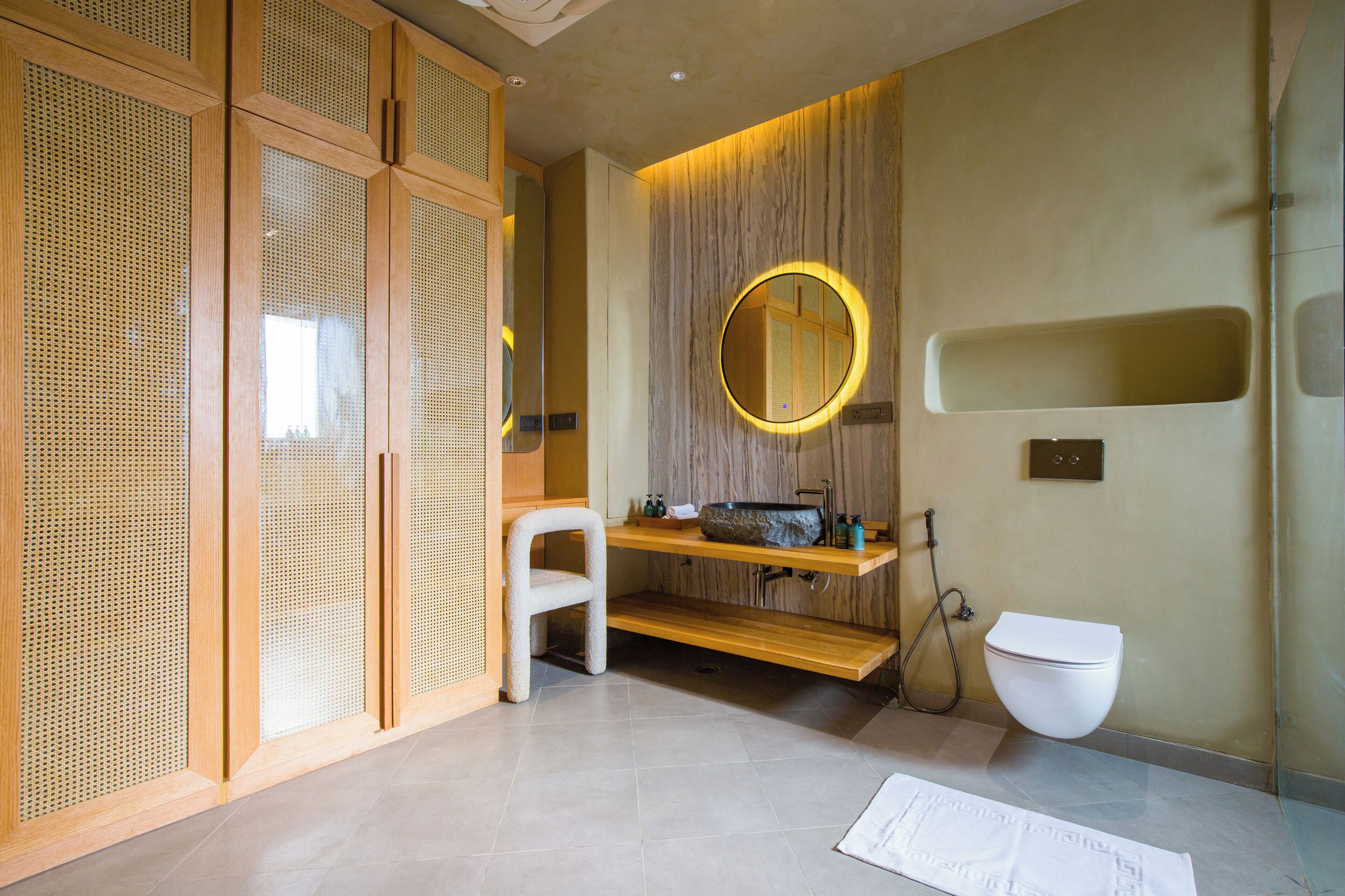Een moderne badkamer met een houten wastafel, een ronde spiegel, een toilet en een douchehoek.