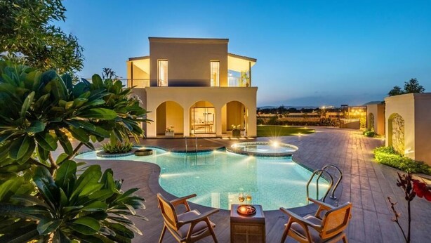 A modern building with a swimming pool, outdoor seating, and arched doorways. - Elivaas Villa Fiorita Stuning 3BHK Villa (Jamwa Ramgarh)