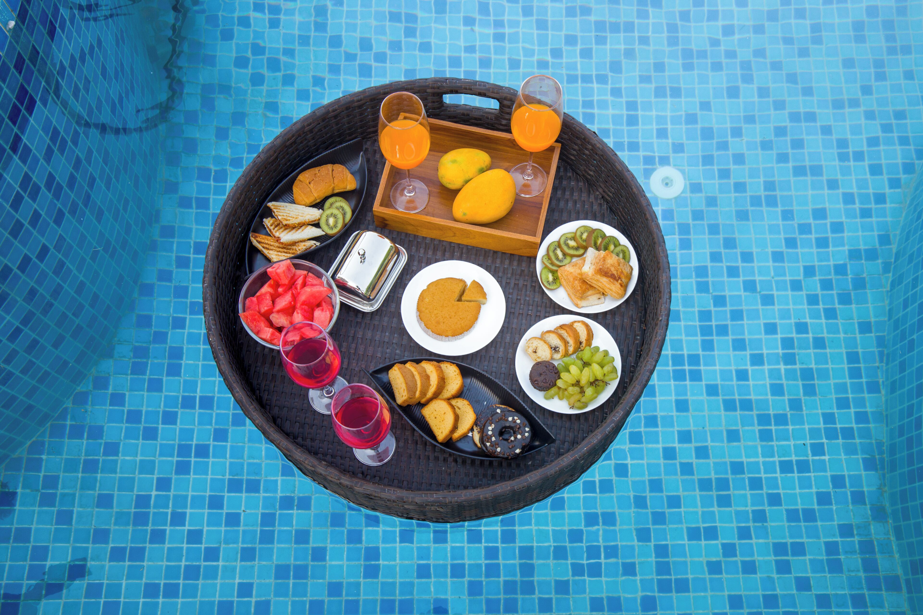 Un buffet varié, avec différents plats et boissons, est installé au bord de la piscine.