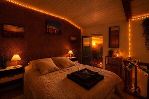 Et soveværelse med seng, to sengeborde, en lampe ved hver side, et vindue med udsigt og en dør til et udendørs område.