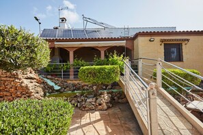 Ein Gebäude mit einer Solaranlage auf dem Dach, einer Steinmauer und einem kleinen Wasserspiel.