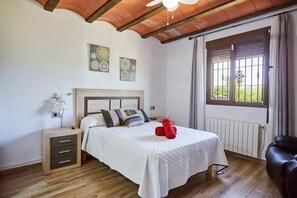A bedroom with a bed, a nightstand, a window with curtains, and a radiator. - Villa 'Vega' with Mountain Views, Wi-Fi, and Air Conditioning (Pozo alcon jaen)