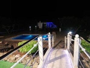 A nighttime view of a swimming pool area with a slide, surrounded by greenery and a stone pathway. - Villa 'Vega' with Mountain Views, Wi-Fi, and Air Conditioning (Pozo alcon jaen)