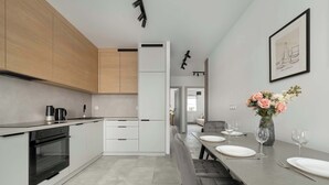 Una cocina moderna con horno empotrado, un comedor con mesa dispuesta para dos personas y una obra de arte enmarcada en la pared.