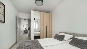 Un dormitorio moderno con una cama grande, un armario y un pasillo que lleva a un baño.