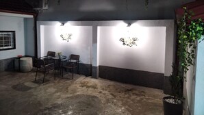 Une terrasse extérieure avec deux tables et des chaises, une plante en pot et des éléments décoratifs fixés au mur.