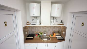Cocina compacta con dos cafeteras, un hervidor, un fregadero, una estufa y un juego de té.