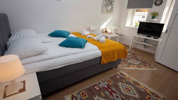 Une chambre d’hôtel moderne équipée d’un lit, d’un bureau, d’une télévision et d’une fenêtre donnant sur un paysage agréable.