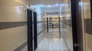A corridor with doors, a reception area, and a ceiling with recessed lighting. - Hotel Kalp Rooms (Vyara)