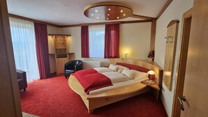 A hotel room with a large bed, a desk, a chair, and a wardrobe. - Gasthof Gutmann (Eberstein)