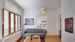 Ett modernt vardagsrum med en grå soffa, ett soffbord i trä och en hängande lampa.