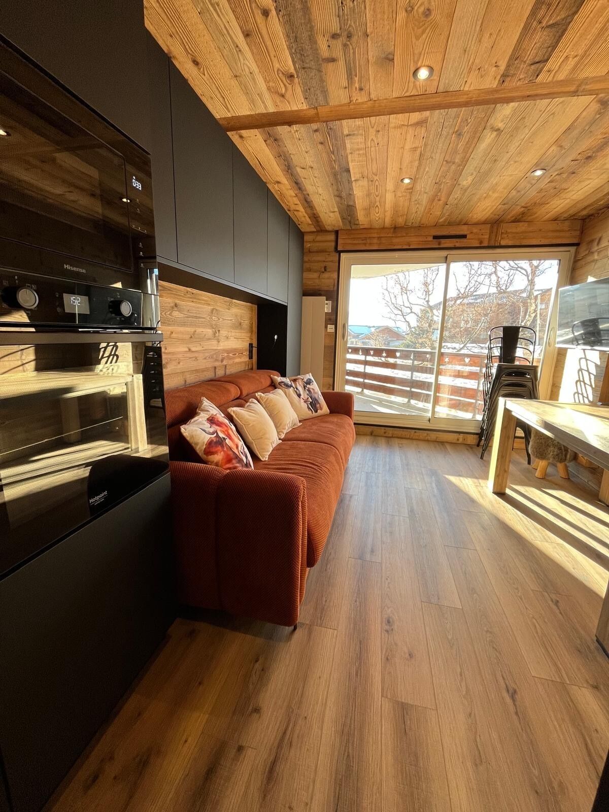 A modern kitchen with a built-in oven and a wooden ceiling.
