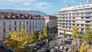 Un immeuble à plusieurs étages doté de balcons, d’un parking et d’arbres au premier plan.
