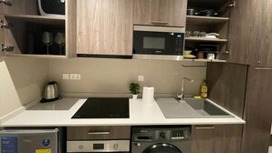 A compact kitchen with a microwave, sink, and built-in dishwasher. - The Bantree by RoyalRest (Accra)