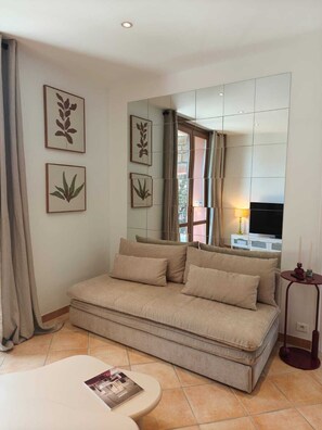 A modern living room with a sofa, a small table, and framed botanical prints on the wall. - Horizon Apartment (Ota)