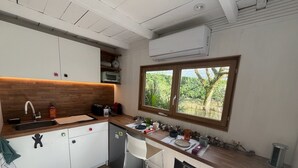 Una cocina moderna con armarios blancos, encimera de madera, horno integrado y ventana con vistas a zonas verdes.