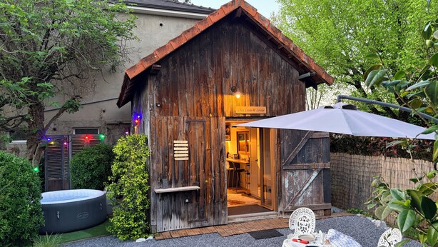 Un edificio de madera rústico con un letrero que dice 'Chez Louis & Louise', un jacuzzi y asientos al aire libre.