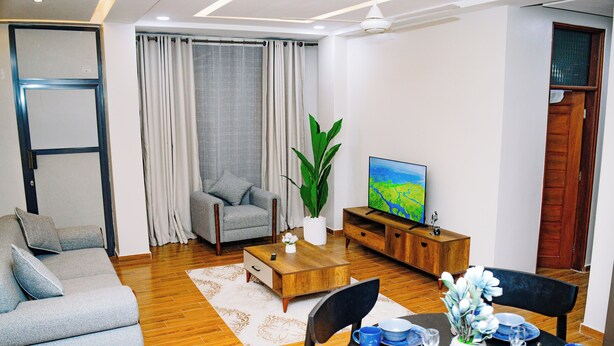 Ein Wohnzimmer mit Sofa, Fernseher, Couchtisch und Essbereich mit blauem Geschirr.